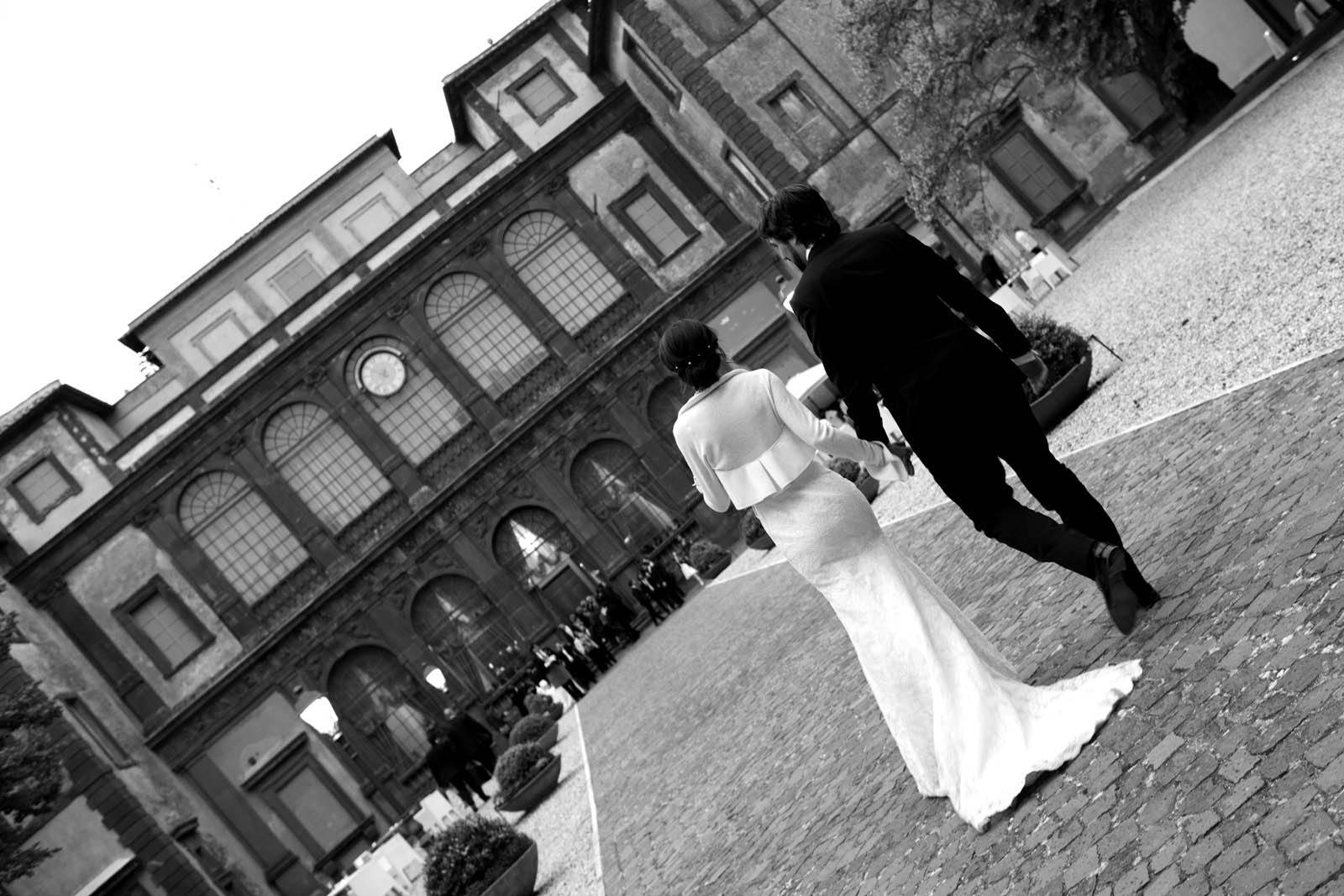 foto in bianco e nero e inclinata a 45 gradi con due sposi di spalle che entrano a Villa Mondragone