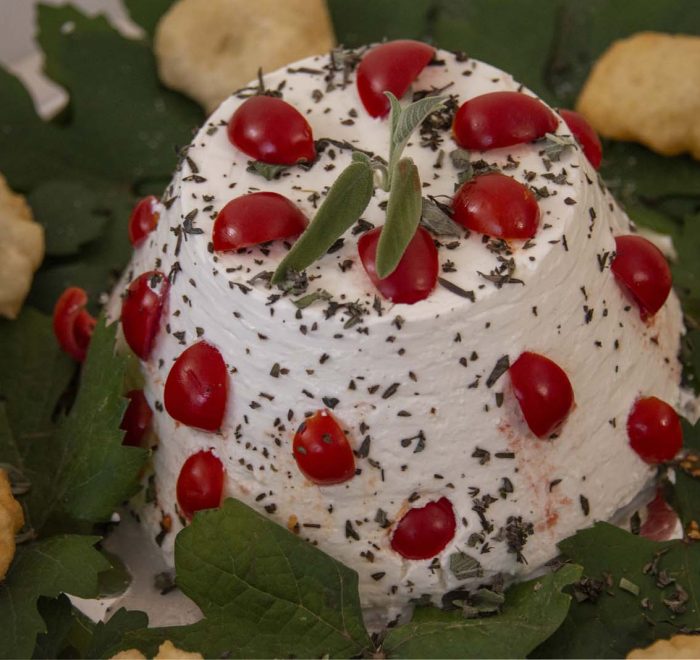 forma di ricotta guarnita con pomodorini pachino, salvia ed erbette