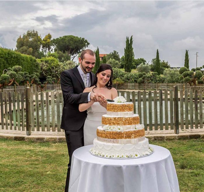 taglio torta all'aperto di sposi felici